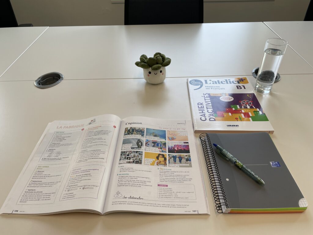 L’atelier+ French textbook open on a table at FTC Paris with workbook, notebook and pen – B1 level