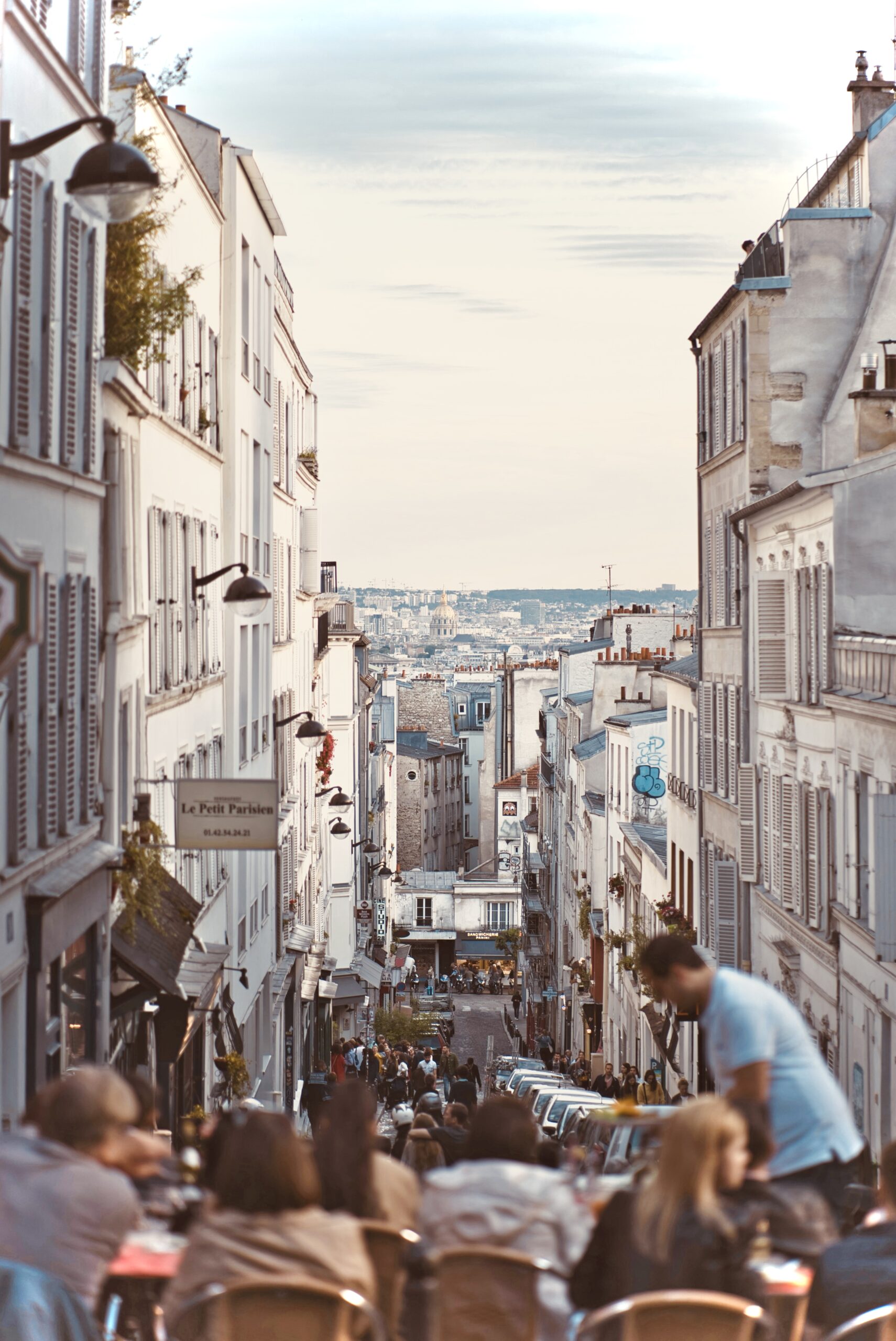 Students learning French in Paris on a lively terrace, with the golden dome of Les Invalides in the background.